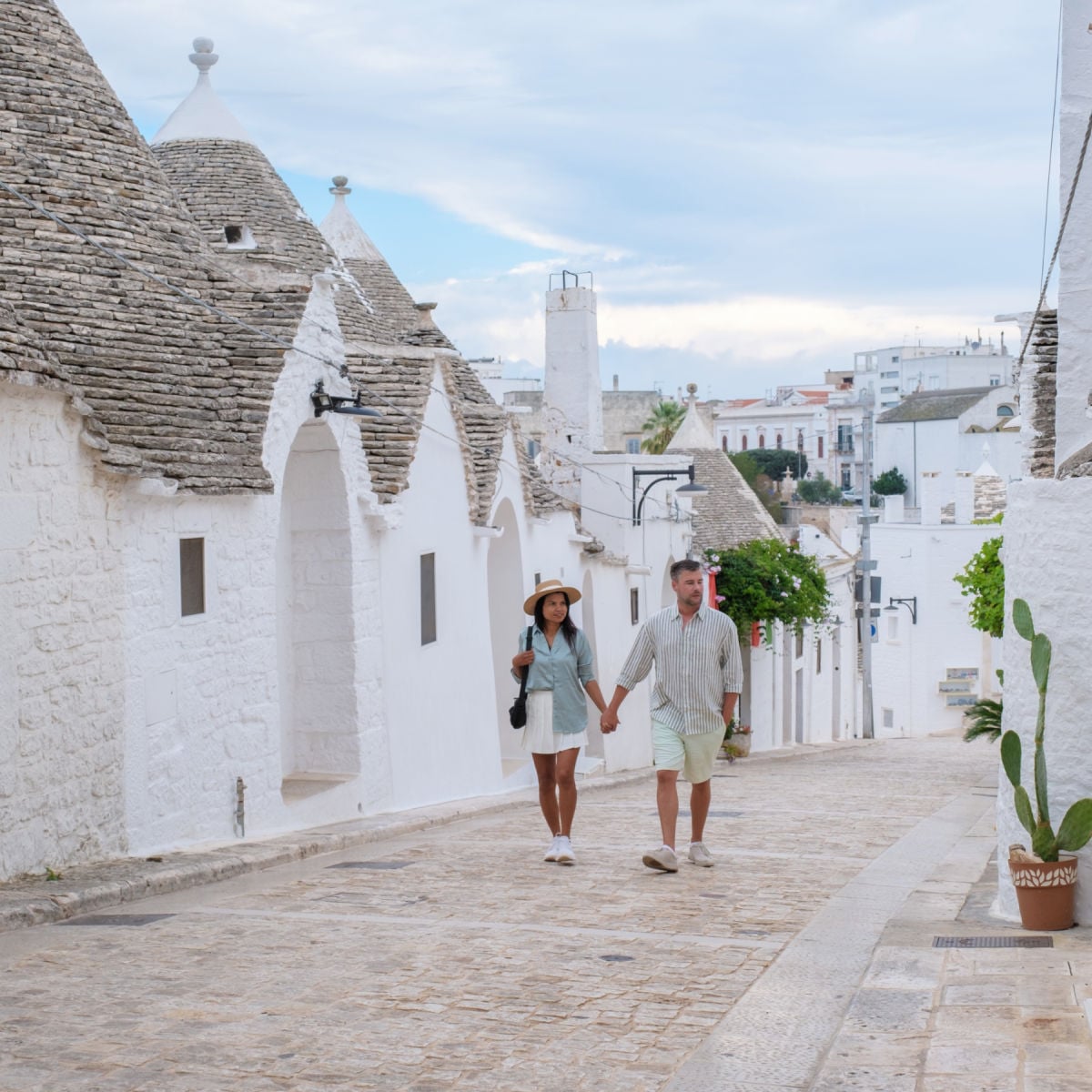 Couple walking through whitewashed village of Alberobello, Italy