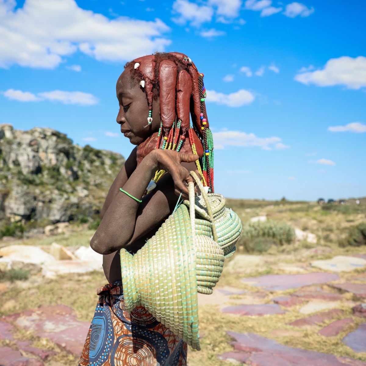 Himba woman carrying a traditional basket in the rugged landscapes of Angola
