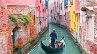 Gondalier guiding tourists through Venice canal