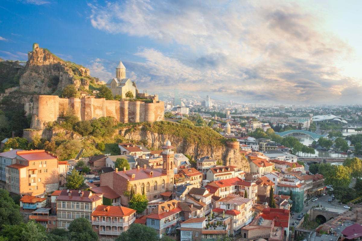Sunny landscape of old Tbilisi and Metekhi Church on the background of blue cloudy sky