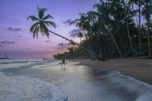 Man swinging on beach in Ghana at twilight