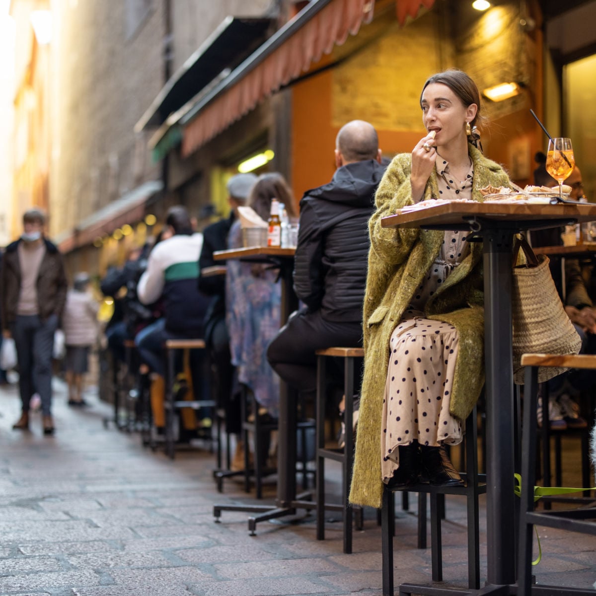 Tourist drinking wine at sidewalk cafe in Bologna, Italy