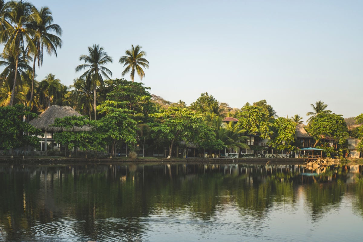 Sunset over tourist village in El Tunco, El Salvador. Cabins covered in palm trees on the banks of the Rio Grande River