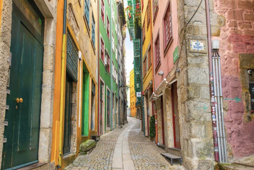A narrow cobblestone alley winding through colorfully painted historic buildings in the old town Ribeira District of Porto Portuga