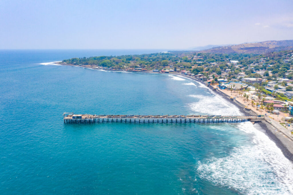 Aerial view of La Libertad beach in El Salvador, where you can see part of the coastal area and its pier of the sea, with a beautiful blue sky.