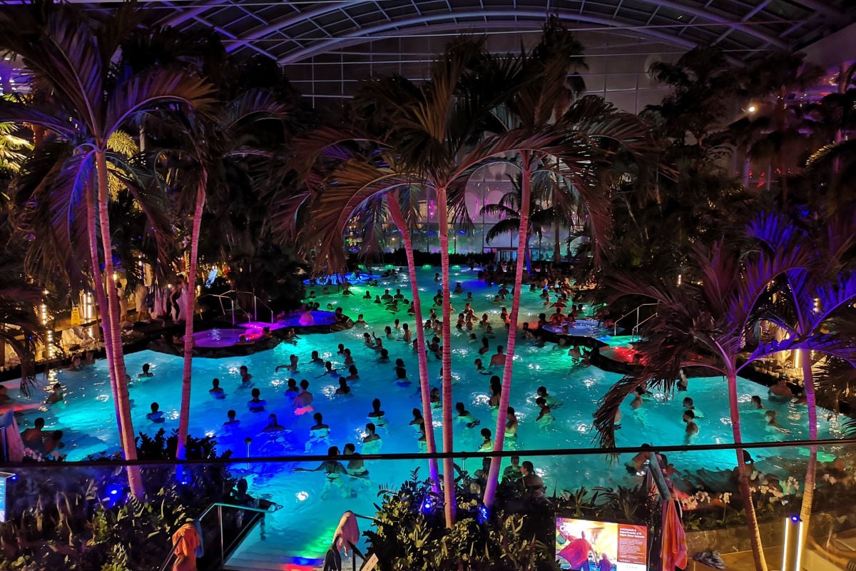 Bucharest, Romania Night view of the indoor palm tree pool area at Therme Bucharest spa with visitors relaxing in the water.