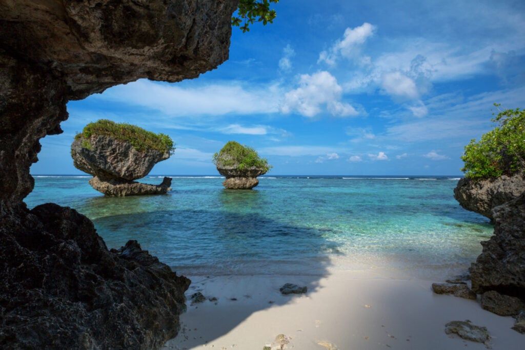 Beautiful rock formations along the sandy beach of Tanguisson Beach on the tropical island of Guam during the morning calm of the ocean on a clear, sunny day