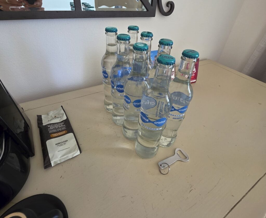 Extra-water-bottles-in-Hotel-Room-at-Sandos-Cancun-Resort-Bottle-opener-on-table.-Original-Photo-By-Trevor-Kucheran