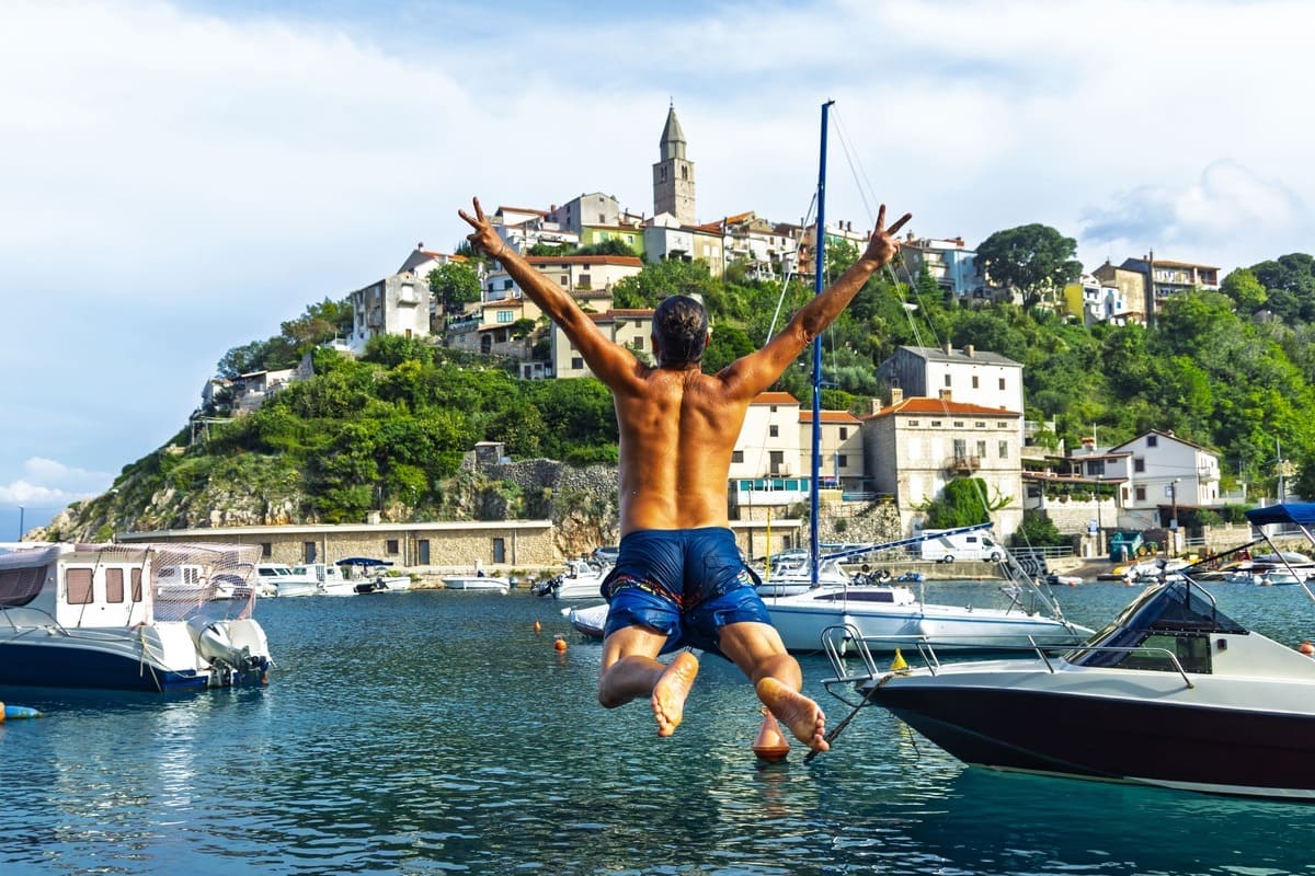 Male Tourist Jumping Into The Water In Vrbnik Harbor, Krk Island, Croatia