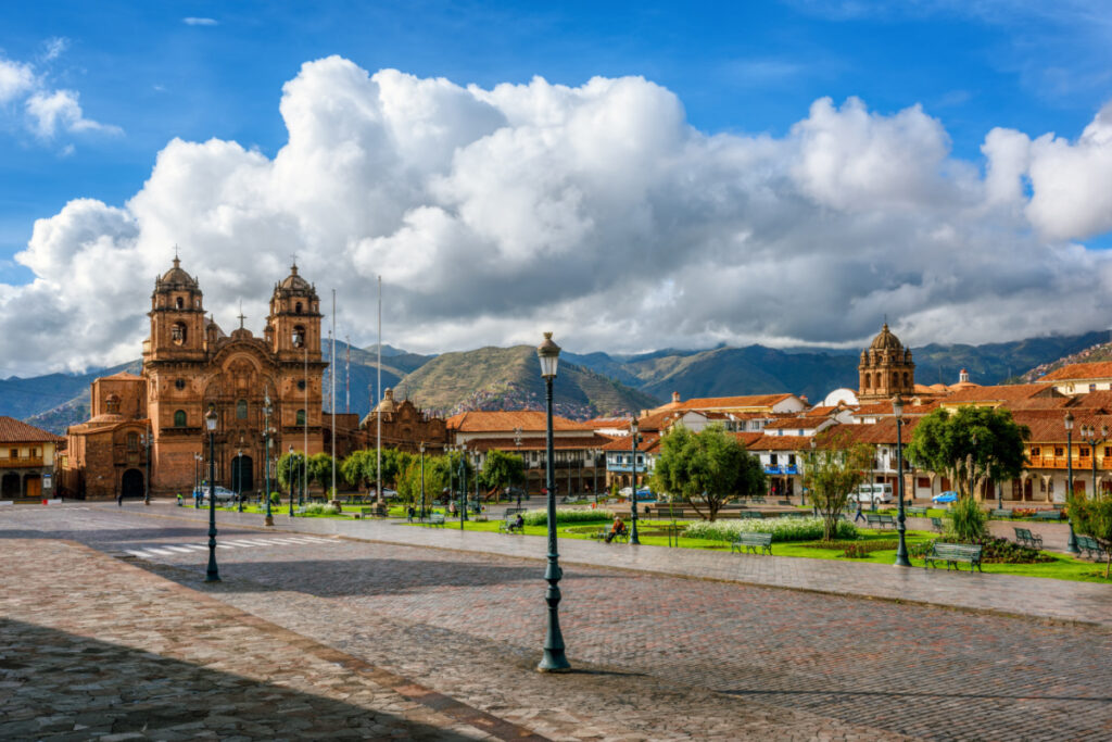 Plaza Mayor and Cusco cathedral in the Old town of Cusco city, and the Andes mountains, Peru. Plaza Mayor or Plaza de Armas is the main square of Cuzco, famous for historical colonial architecture.