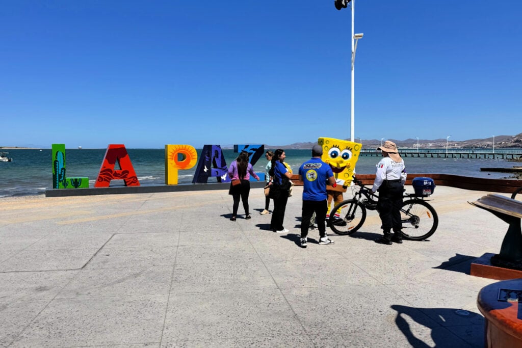 Tourism police in La Paz being friendly with visitors in front of the La Paz sign on the boardwalk