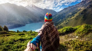 Woman overlooking mountains in Peru while the sun comes through the clouds and a beautiful lake is below (1)