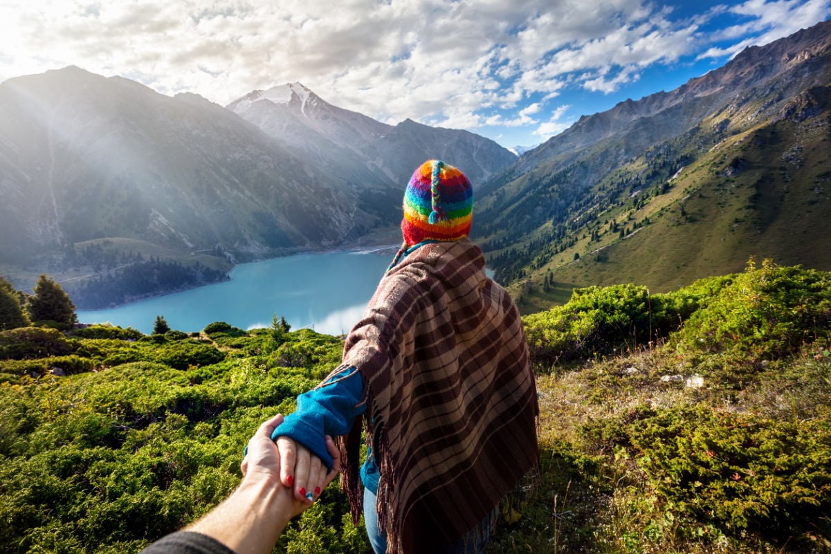 Woman overlooking mountains in Peru while the sun comes through the clouds and a beautiful lake is below (1)