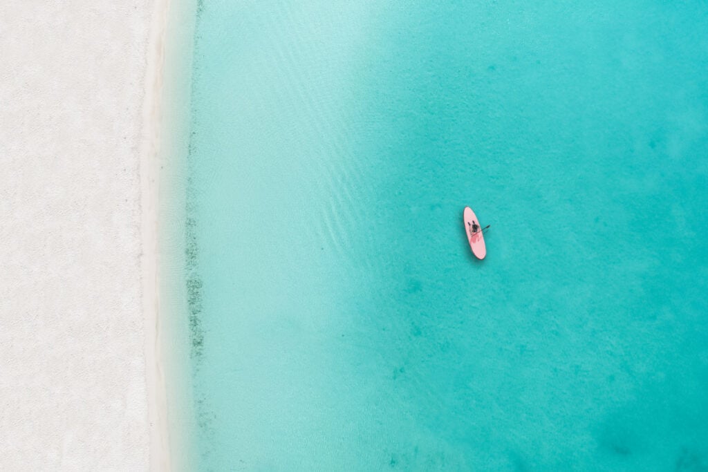 Drone photo of beach in Grace Bay, Providenciales, Turks and Caicos. The caribbean blue sea and underwater rocks can be seen, as well as some jet skies