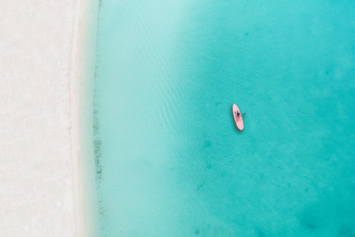 Drone photo of beach in Grace Bay, Providenciales, Turks and Caicos. The caribbean blue sea and underwater rocks can be seen, as well as some jet skies
