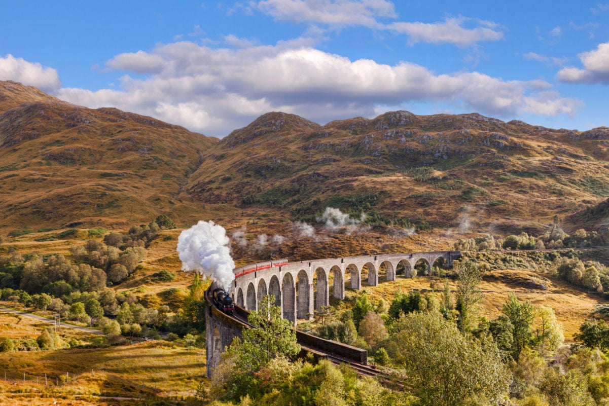 Glenfinnan Viaduct and the Jacobite steam train blowing steam from the exhaust as it crosses the Glenfinnan Viaduct, Highland, Scotland, UK.