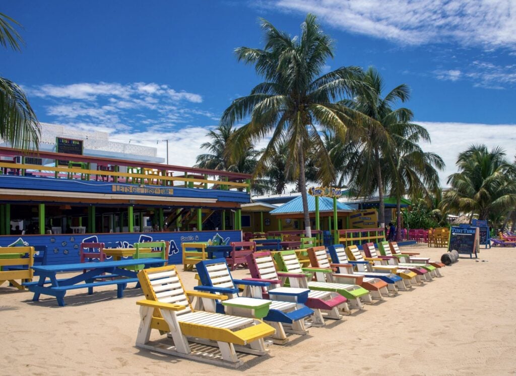 Colourful wooden sun beds outside the beachfront Tipsy Tuna bar on Placencia Beach,