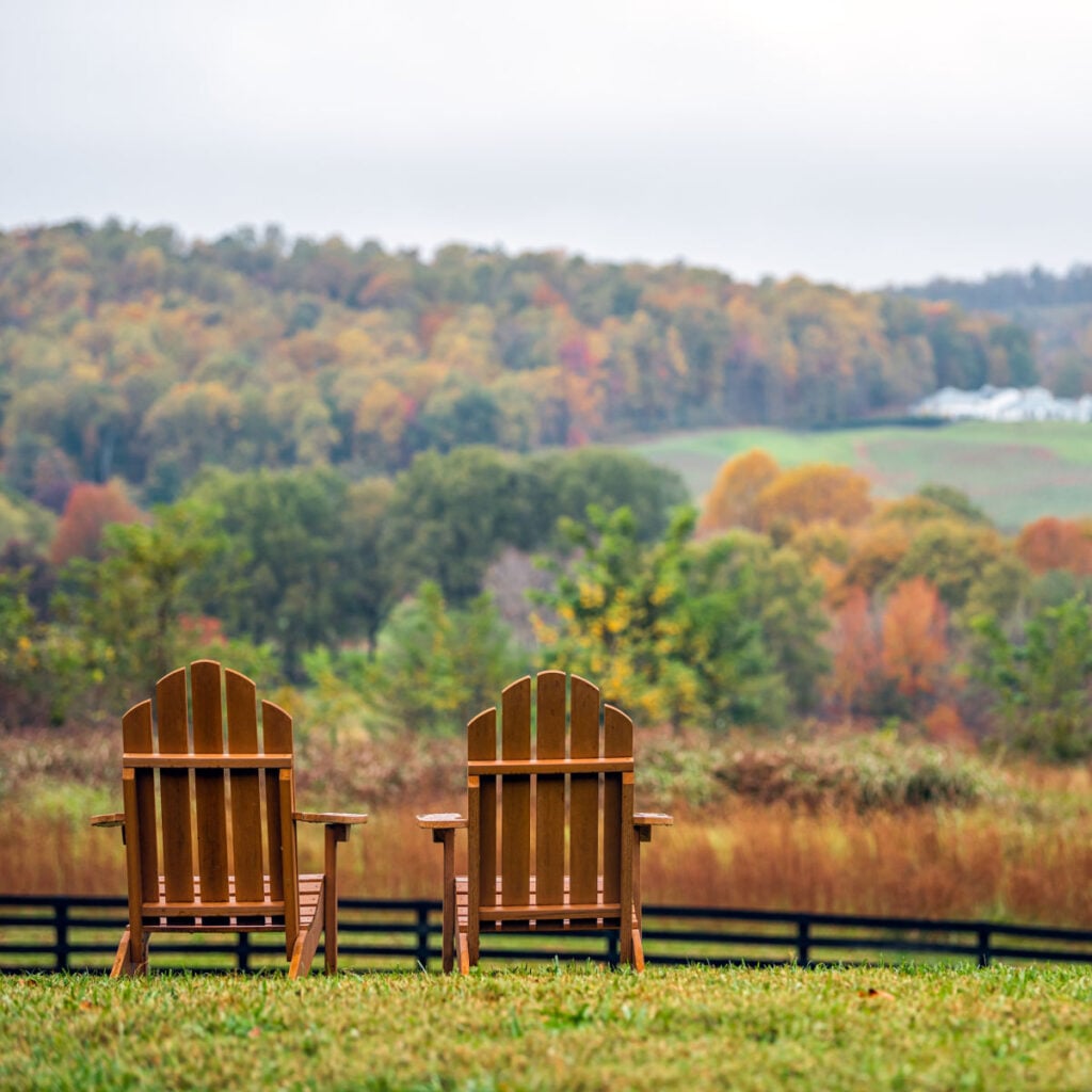 Empty wooden chairs in autumn fall foliage season countryside at Charlottesville winery vineyard in blue ridge mountains of Virginia with cloudy sky day
