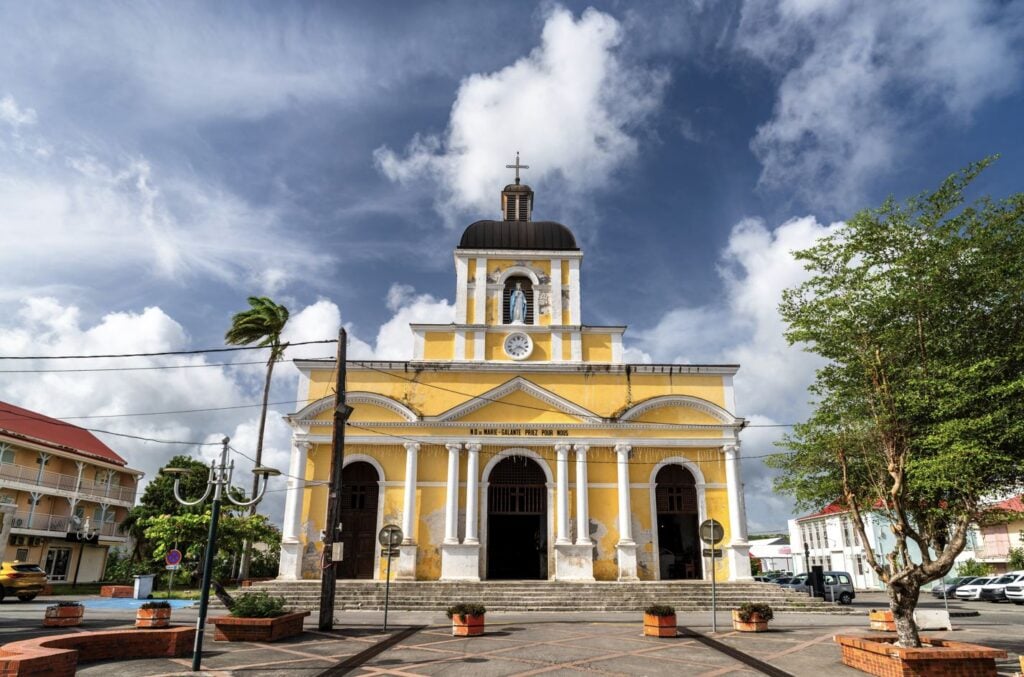 Facade of the Notre-Dame-de-l'Assomption church under a cloudy sky in Grand-Bourg, Marie-Galante Island, Guadeloupe