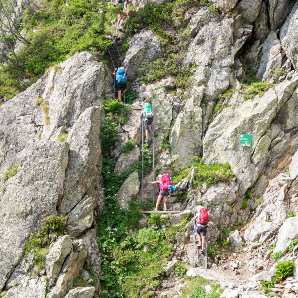 Hikers climbing the dramatic ladder sections immediately after the Aiguillette d'Argentiere. Part of the scenic Tour of Mont Blanc hiking route, on the French Alps
