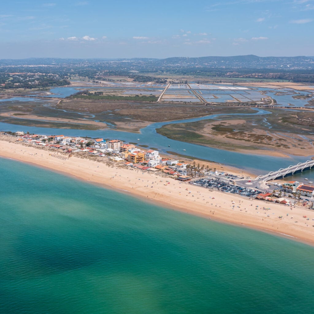Praia de Faro along the coast in Ria Formosa, Algarve, Portugal, captured from above with clear water and land outlines on a sunny day